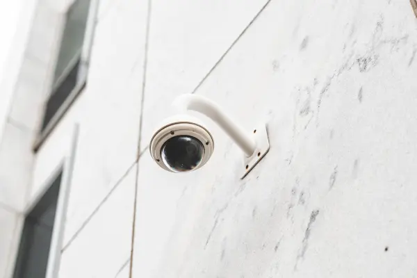 A white color camera hanging on the wall.