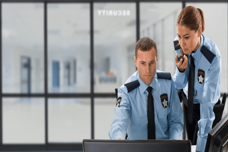 Two security guards working on a laptop.