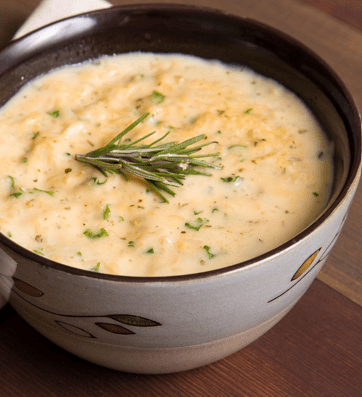 Creamy soup with rosemary garnish in bowl.