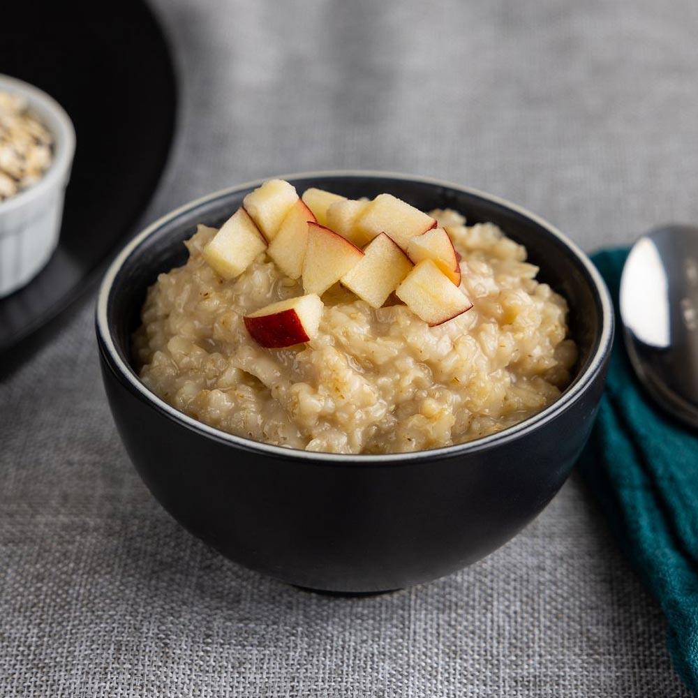 Bowl of oatmeal with apple slices.