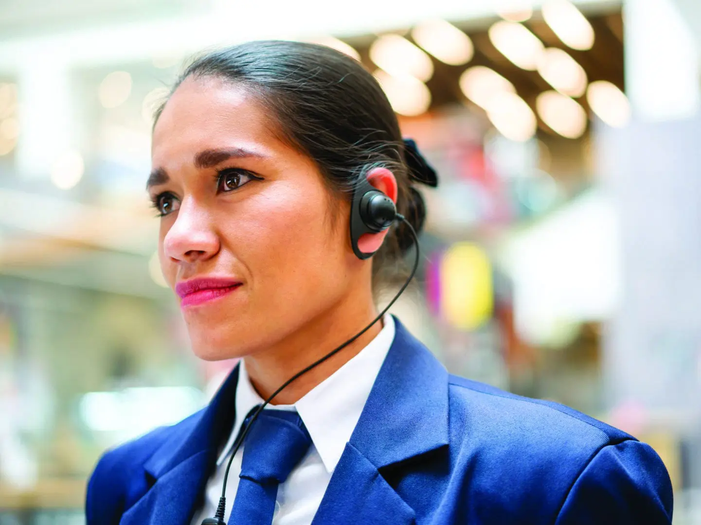 Woman in blue suit wearing headset.