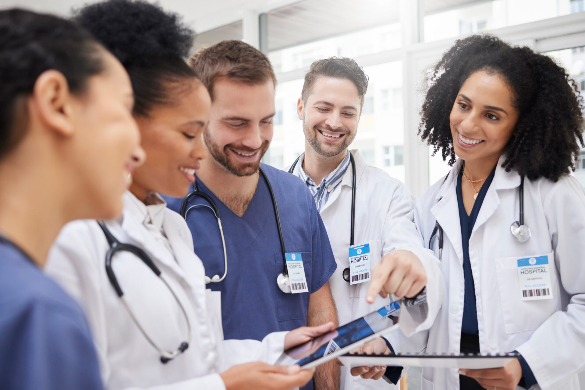 Doctors, tablet and meeting in team discussion on x ray, MRI or brain scan in surgery planning at hospital. Group of happy medical or healthcare professionals with technology in teamwork at clinic